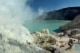 Het turquoise zure kratermeer van Kawah Ijen, met mijnwerkers die zwavel winnen tussen de rook.