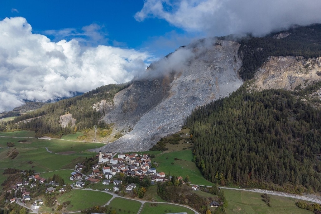 Luchtfoto van het dorp Brienz in Graubünden met de afgebrokkelde puinhelling van de berg erboven.