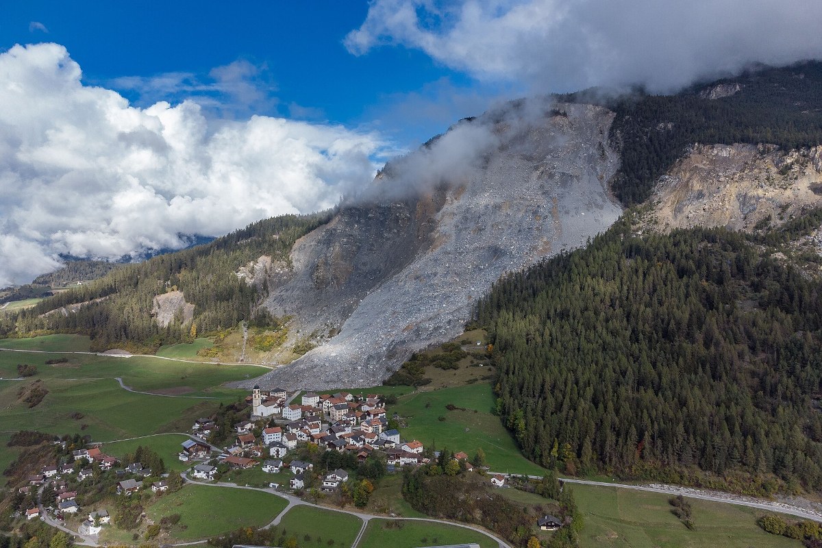 Luchtfoto van het dorp Brienz in Graubünden met de afgebrokkelde puinhelling van de berg erboven.